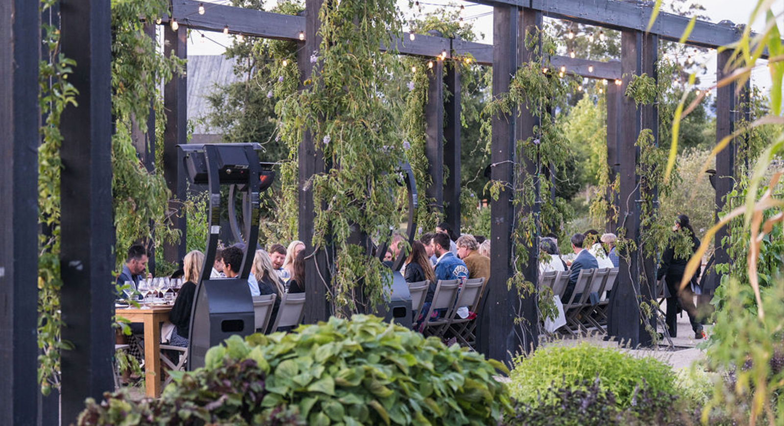 Photo of the whole group seated at the dining table with the Stanly Ranch garden in the foreground.
