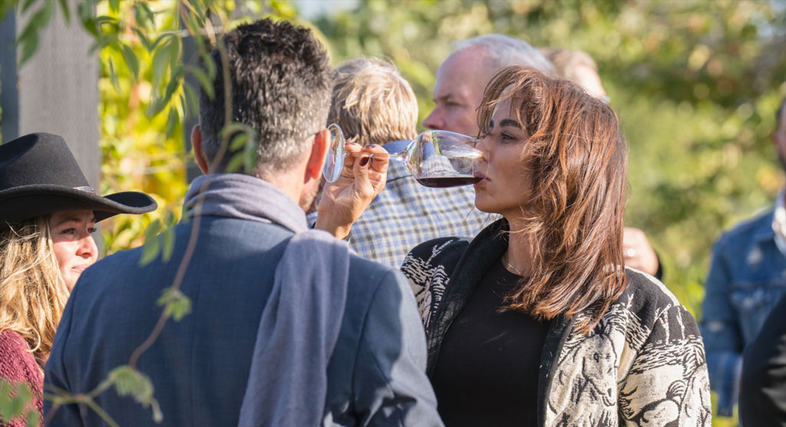 A woman drinking a glass of wine as she talks with friends during the cocktail hour.