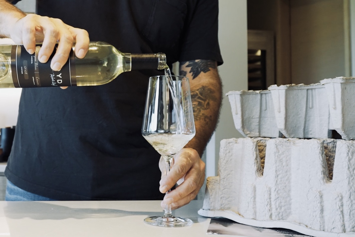 Lloyd Cellars wine being poured beside recyclable molded pulp shipping inserts