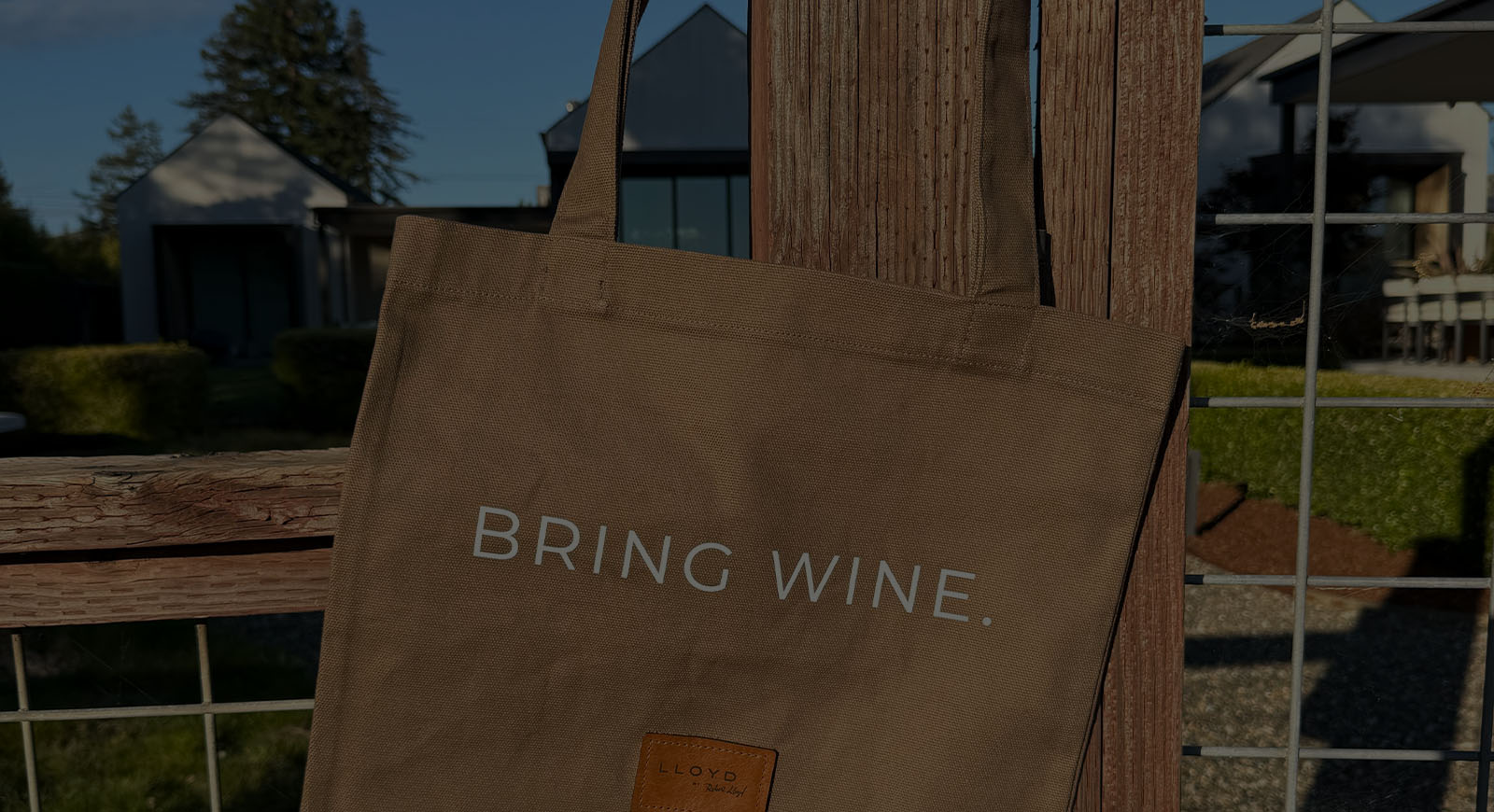 Lloyd Cellars BRING WINE. canvas tote hanging on a wooden fence post