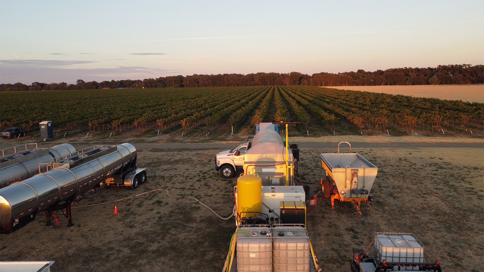 Juice tankers and the mobile press at the edge of the vineyard at dusk, Reamer Farms